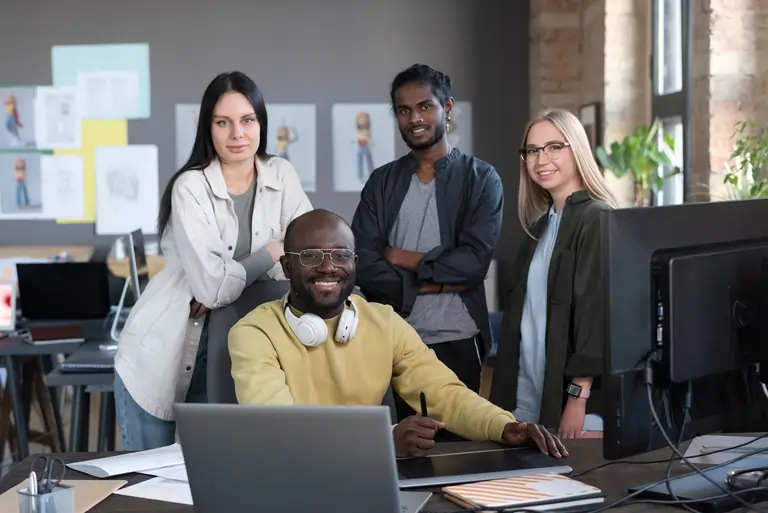 A group of people smiling and working together in a studio